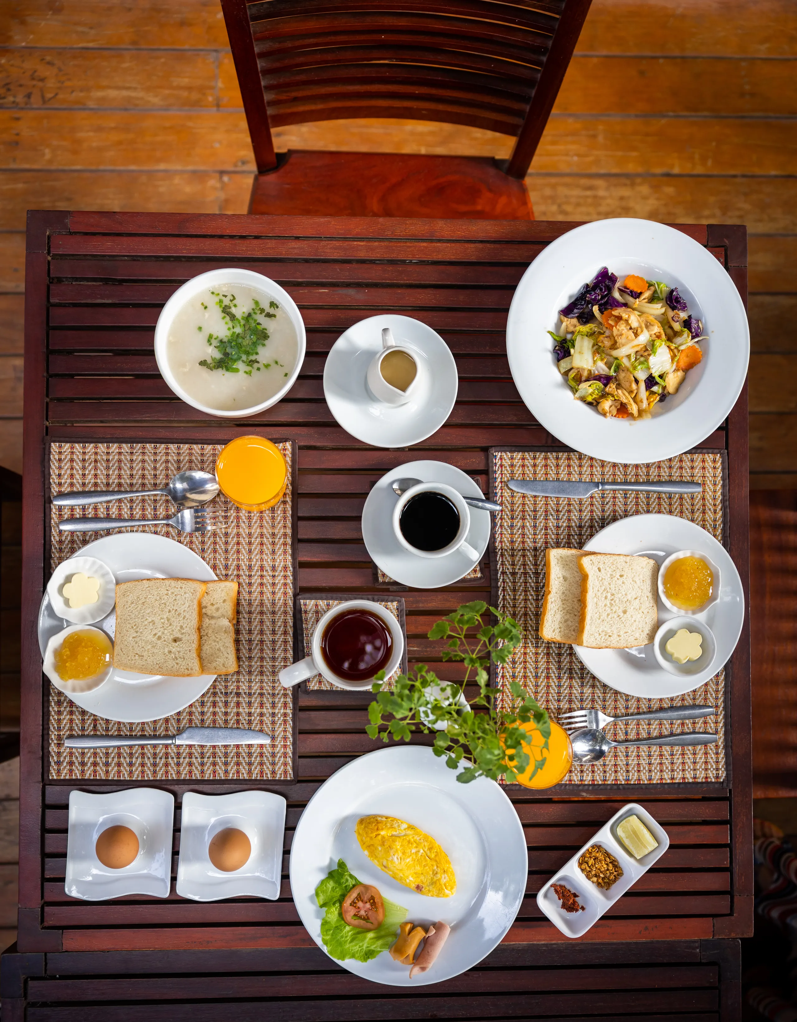 A breakfast of eggs, salad, coffee, juice and toast laid out from above