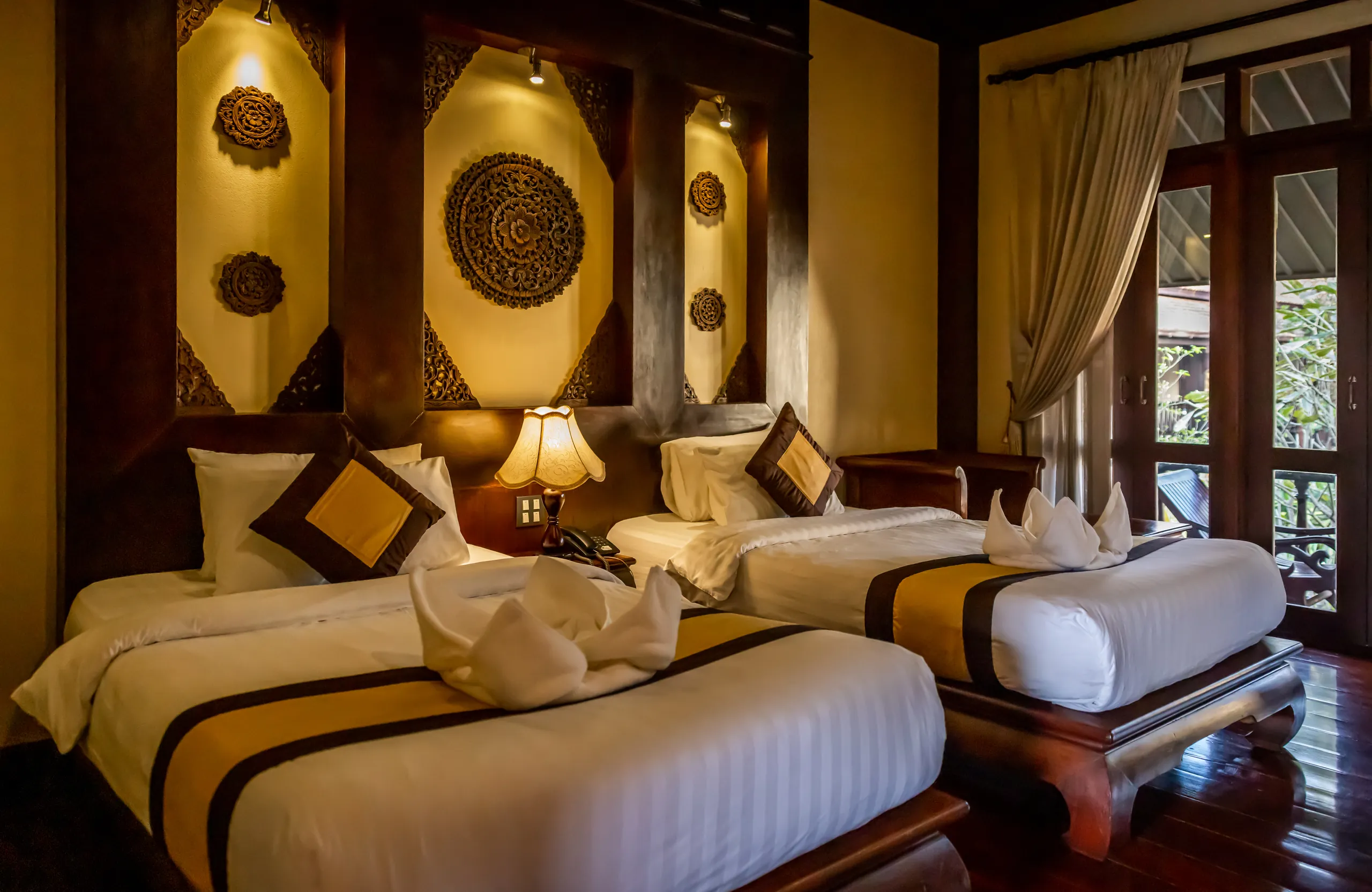 A Deluxe room laid out with two single beds beneath carved timber panels