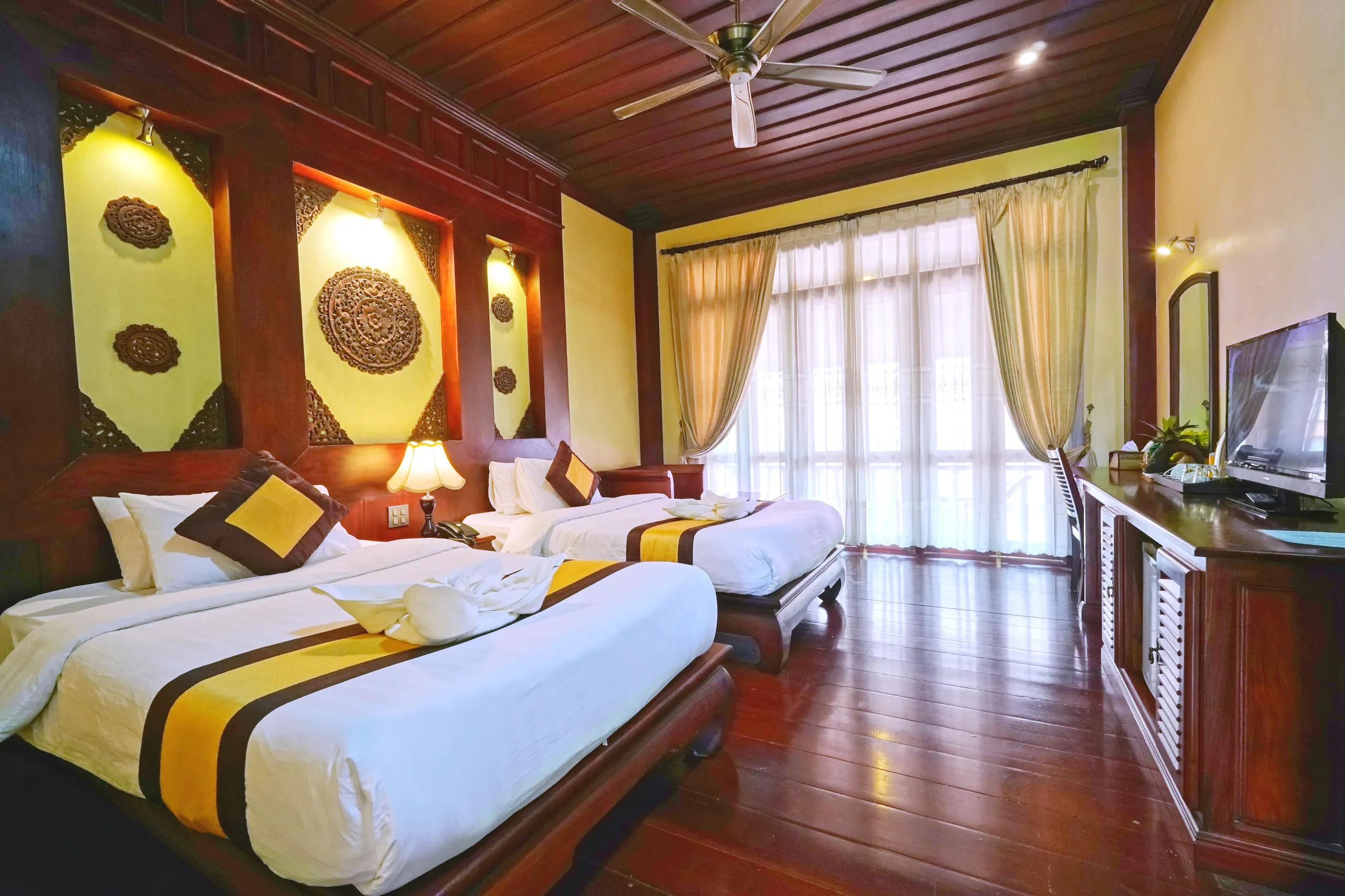 Twin beds beside the balcony doors of a Deluxe room