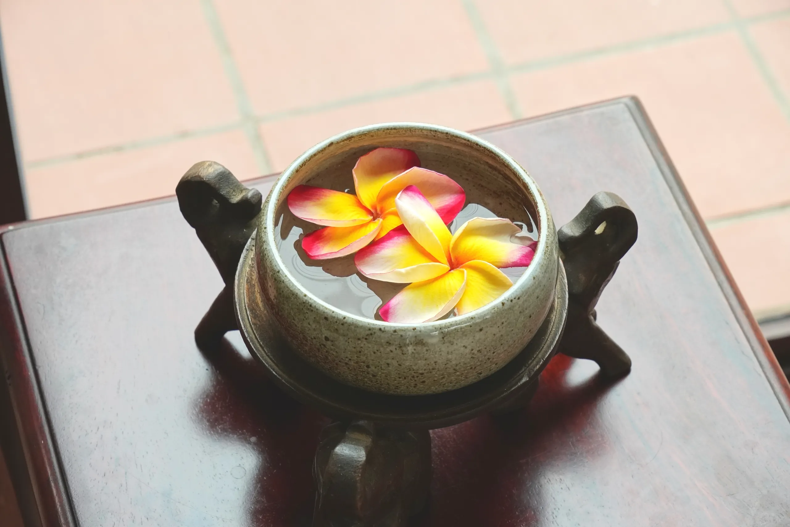 Frangipani flowers floating in a stone bowl