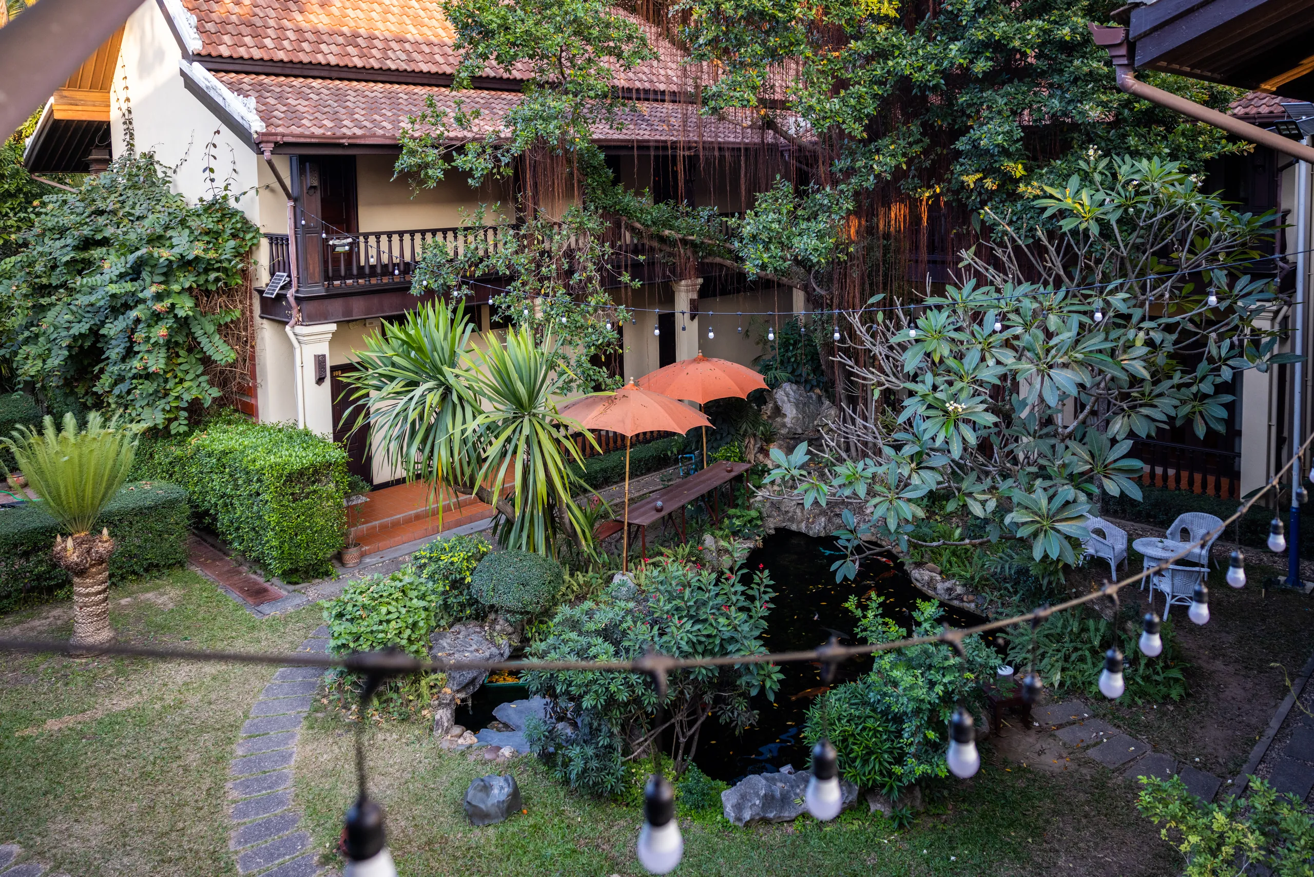 The lawn and garden seen from an upper balcony, with parasols and clipped shrubs