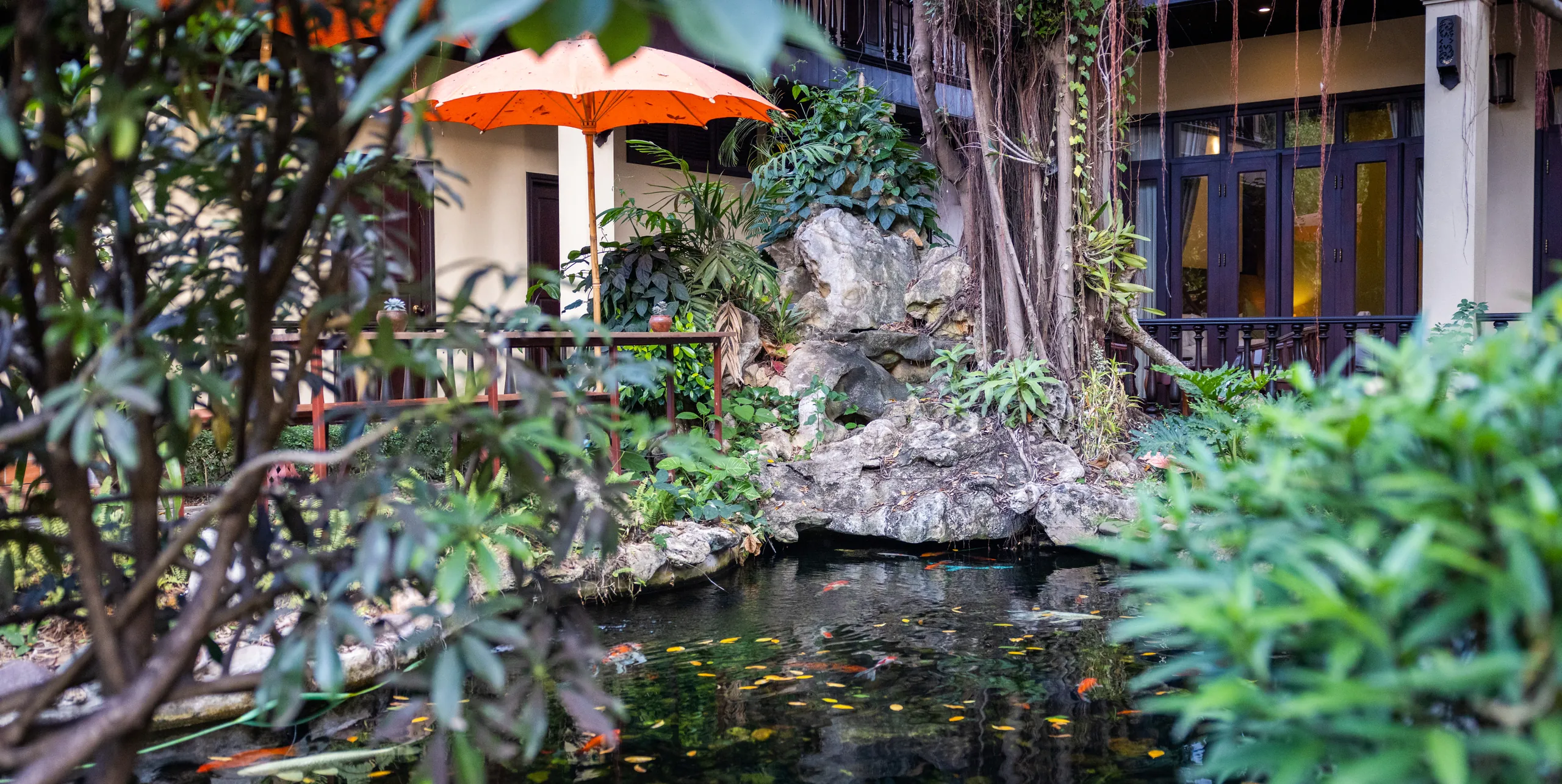 A red parasol beside the rock pond in the hotel garden
