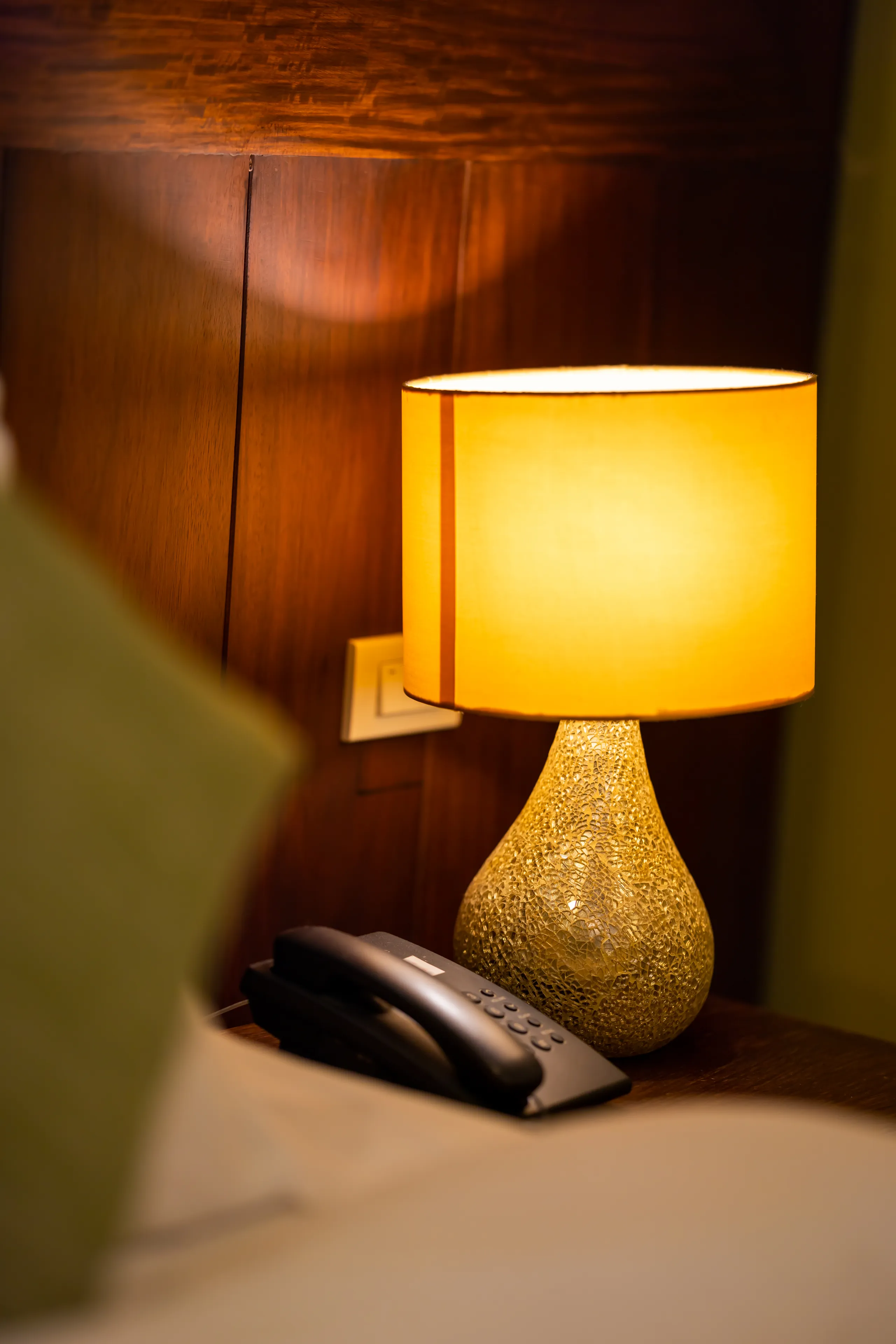 A gilded table lamp glowing against dark timber panelling