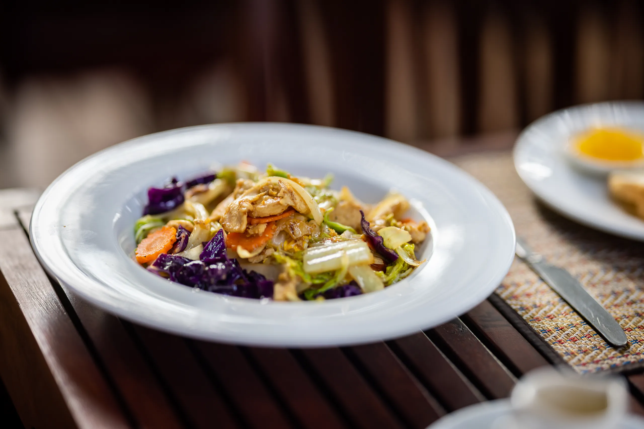 A plated salad of vegetables and herbs on a timber table