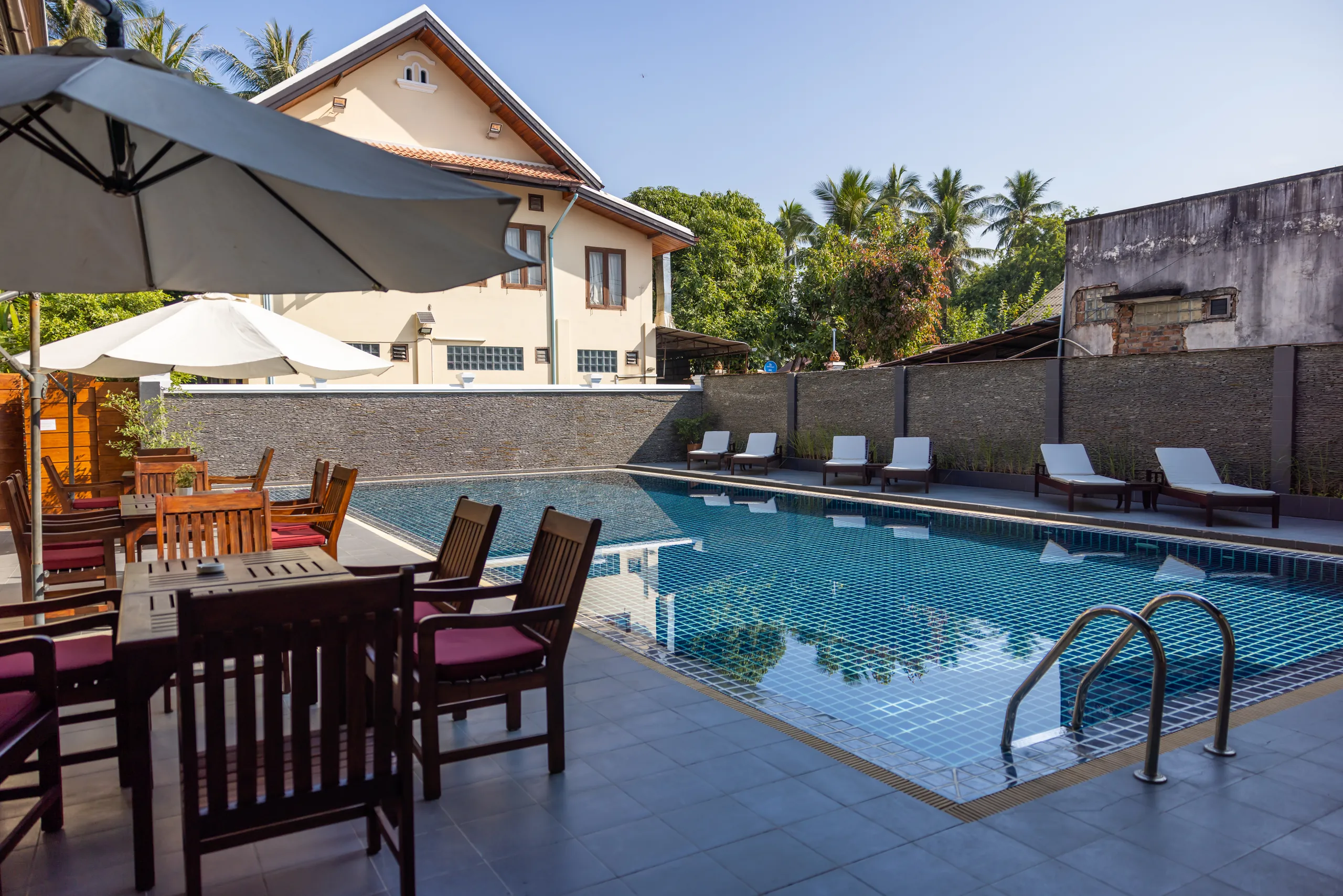 The outdoor swimming pool with loungers and parasols beside the hotel buildings