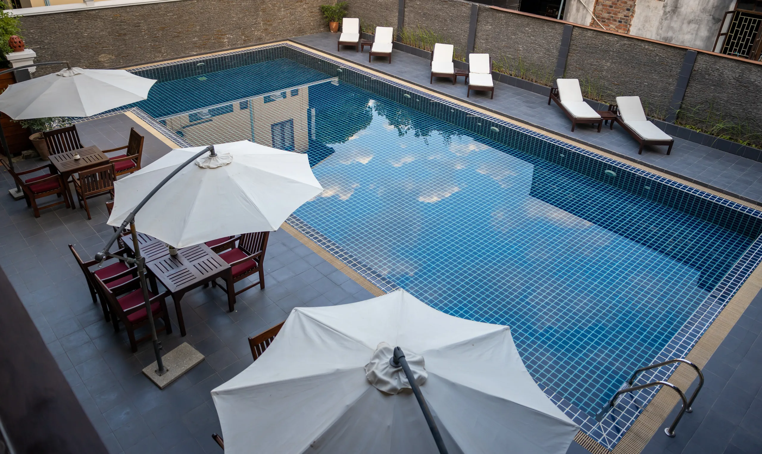 Sun loungers and white parasols along the edge of the swimming pool