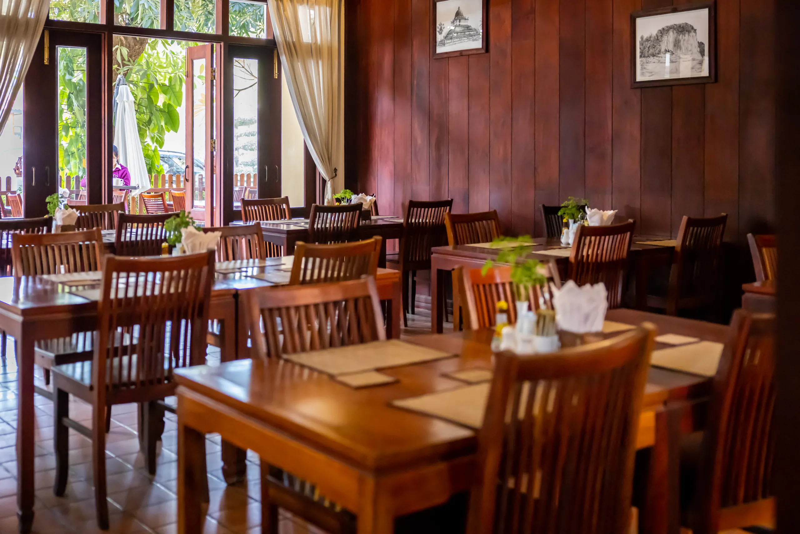Restaurant tables beside windows opening onto the garden