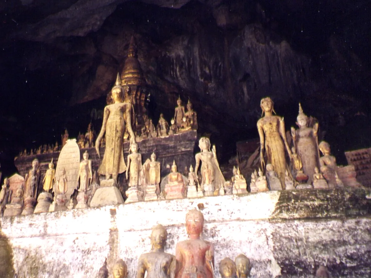 Hundreds of small Buddha figures crowded on ledges inside the Pak Ou caves, beneath the dark cave roof